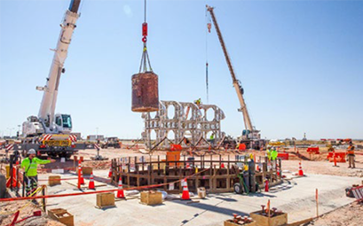 a bucket of excavated dirt is lifted out of the utility shaft